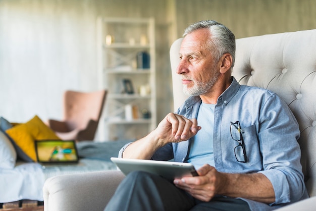 Homme senior envisagé tenant la tablette numérique à la recherche