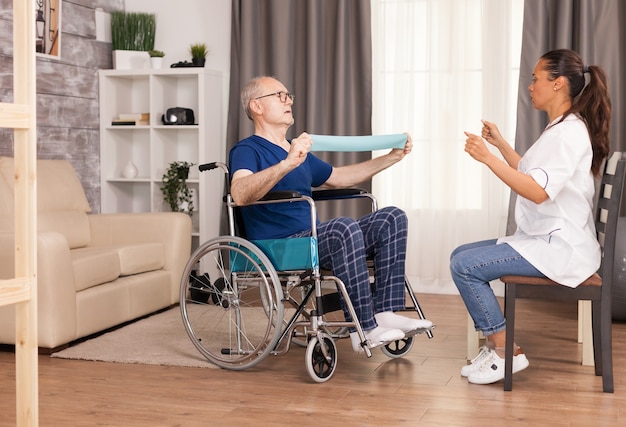 Homme senior handicapé en fauteuil roulant faisant des exercices de récupération avec bande de résistance