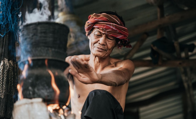 Photo gratuite homme senior torse nu et pagne turban cuit à la vapeur de riz gluant avec un poêle à bois selon la vie des ruraux, espace de copie, scène rurale de la campagne en thaïlande