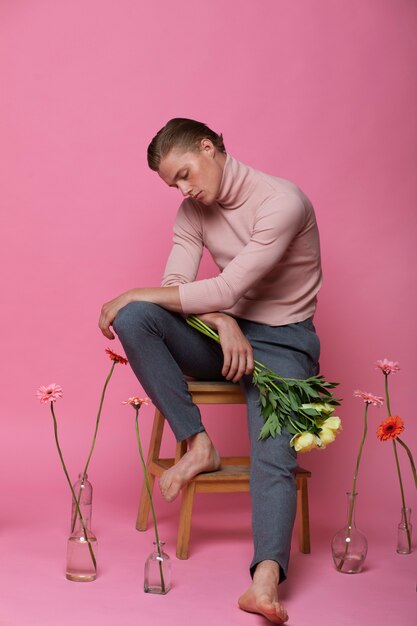 Photo gratuite homme sensible plein coup posant avec des fleurs