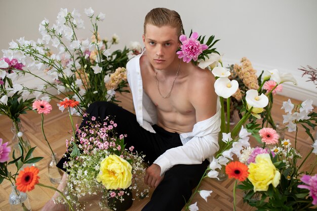 Homme sensible posant avec des fleurs grand angle