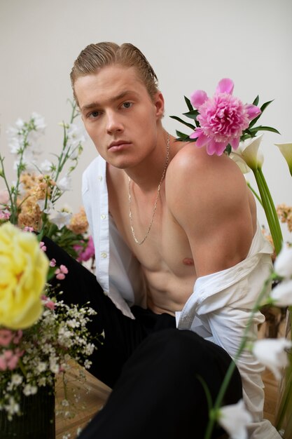 Homme sensible posant avec vue de côté de fleurs