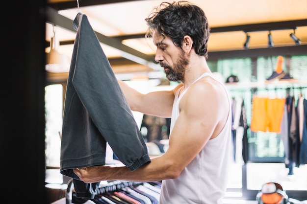 Homme sérieux arrangeant la veste sur des cintres