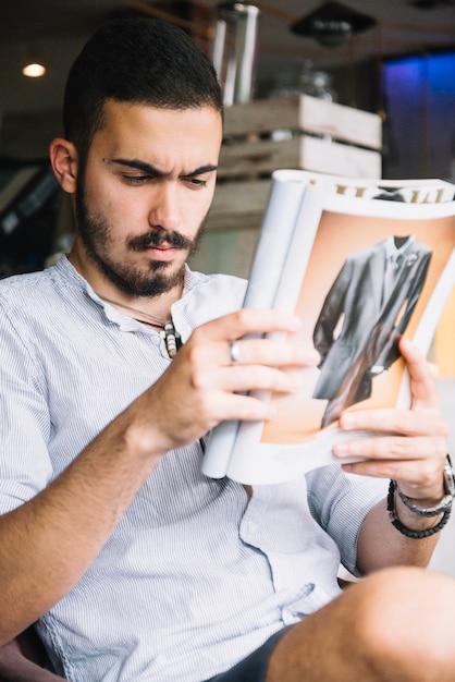 Homme sérieux concentré sur le magazine