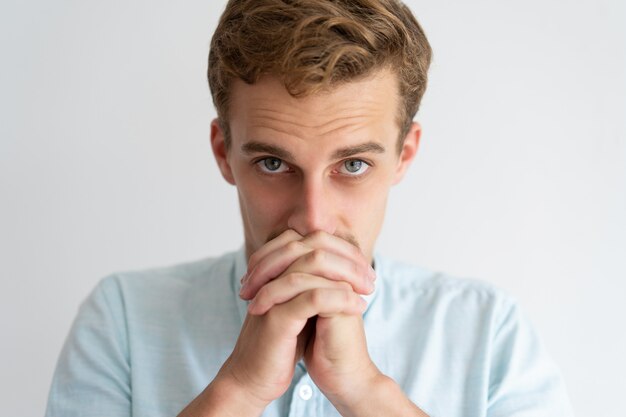 Homme sérieux gardant les mains jointes et implorant quelque chose