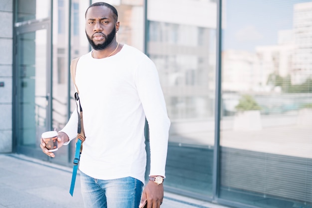 Photo gratuite homme sérieux près du mur de verre