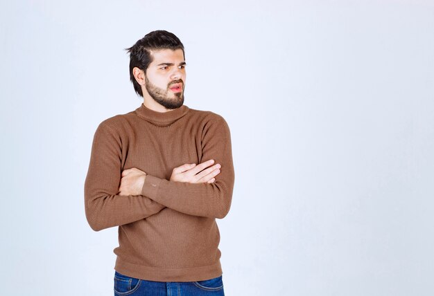 Homme sérieux en regardant la caméra et posant avec les bras croisés.