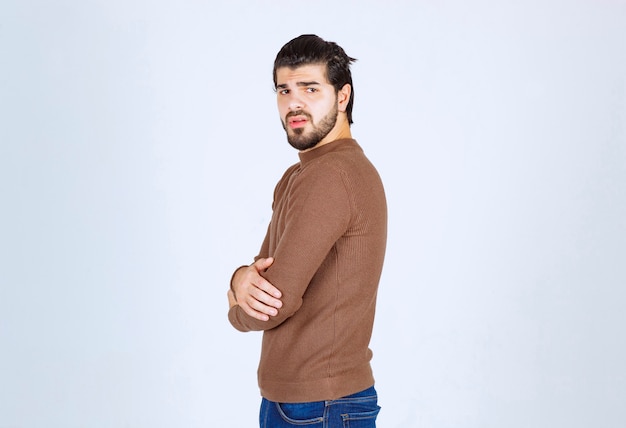 Homme sérieux en regardant la caméra et posant avec les bras croisés.