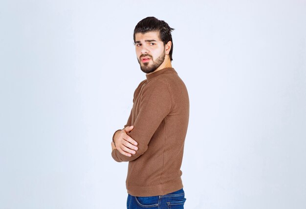 Homme sérieux en regardant la caméra et posant avec les bras croisés.