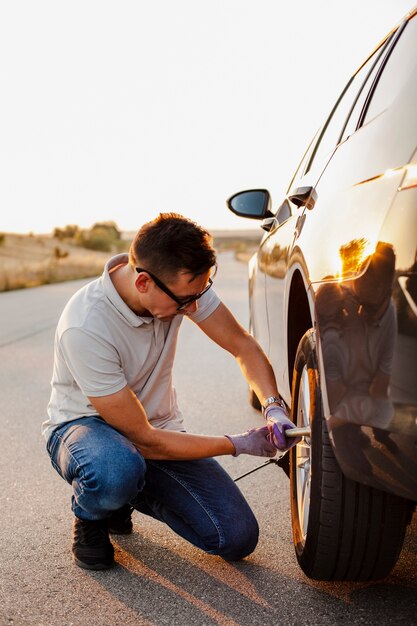 Homme serrant les boulons de la roue de voiture