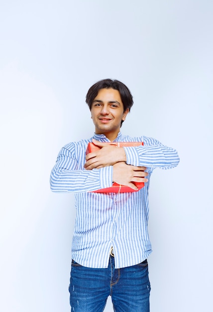 Homme serrant sa précieuse boîte cadeau rouge. photo de haute qualité