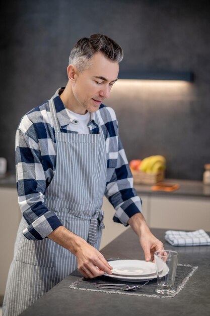 Homme servant une table soigneusement avec de la vaisselle propre