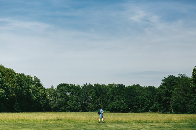 Homme en short bleu marchent le long de la pelouse verte