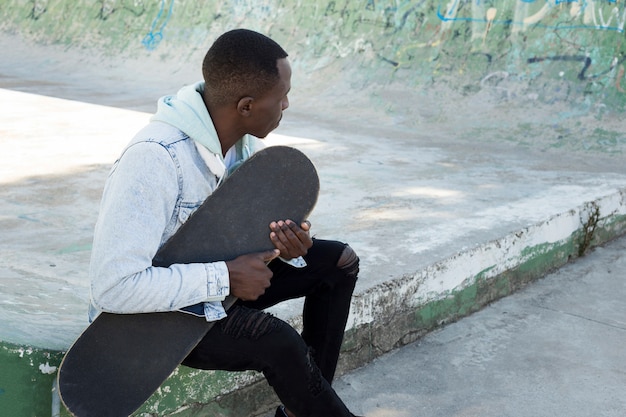 Homme avec skateboard en milieu urbain