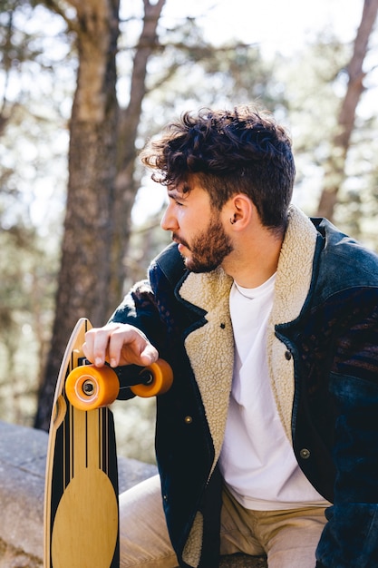 Homme avec skateboard et veste bleue