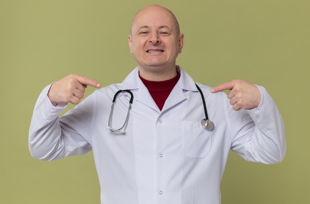 Homme slave adulte souriant en uniforme de médecin avec stéthoscope pointant sur lui-même