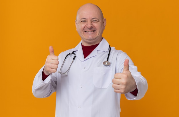 Homme slave adulte souriant en uniforme de médecin avec stéthoscope pouce vers le haut