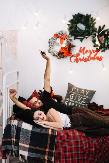 Homme avec smartphone et femme endormie sur le lit