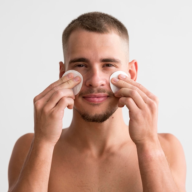 Homme Smiley à l'aide de tampons de coton sur son visage