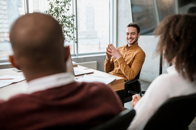 Photo gratuite homme smiley parlant à ses collègues lors d'une réunion