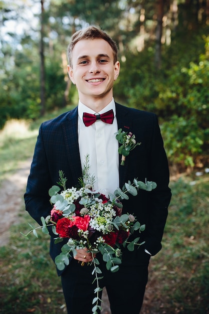 Homme en smoking avec bouquet souriant