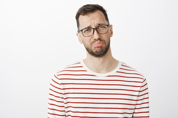 Photo gratuite homme sombre avec une barbe à lunettes, faisant la moue et pleurant, se plaignant à un ami de son petit ami qui a oublié son anniversaire