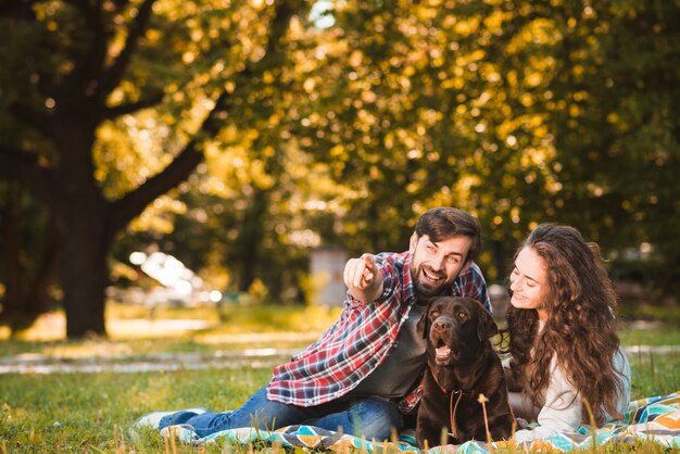 Homme avec son chien et sa petite amie montrant quelque chose dans le parc