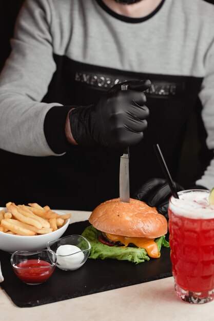 Homme sortant un couteau du hamburger.