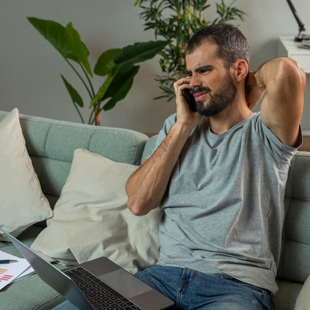 Photo gratuite homme souffrant de douleurs au cou tout en travaillant sur un ordinateur portable à la maison