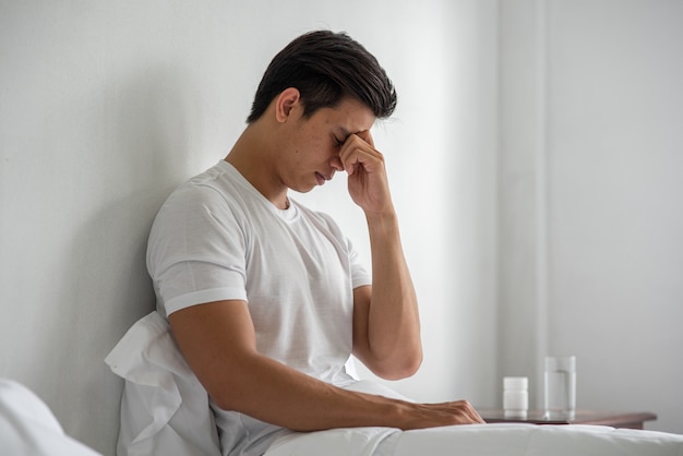 Photo gratuite un homme souffrant de migraines tient sa main par le nez dans le lit.