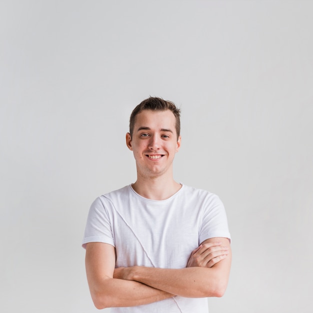 Homme souriant aux bras croisés en regardant la caméra