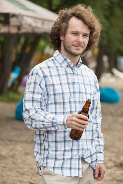 Homme souriant avec de la bière sur la plage