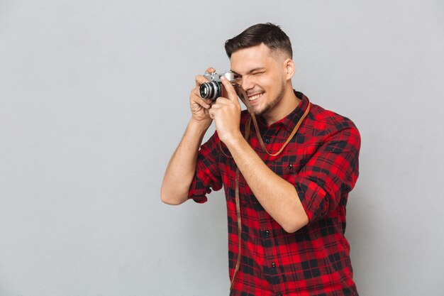 Homme souriant en chemise faisant photo sur appareil photo rétro