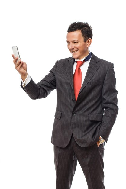 Homme souriant en costume regardant sur un smartphone. Isolé sur fond blanc.