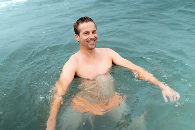 Homme souriant de coup moyen au bord de la mer