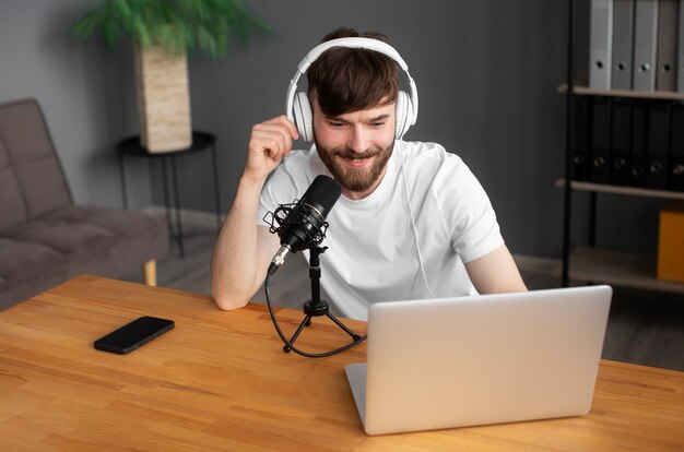 Homme souriant à coup moyen enregistrant un podcast à l'intérieur