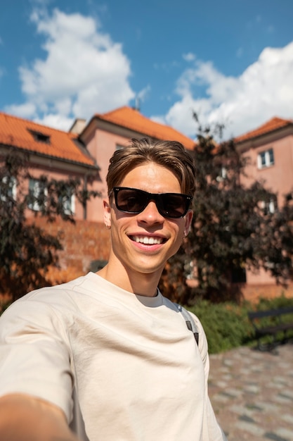 Homme souriant à coup moyen posant avec des lunettes de soleil