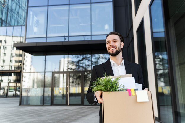 Homme souriant à coup moyen tenant une boîte en carton