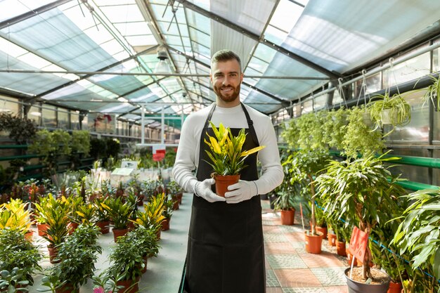 Homme souriant de coup moyen tenant une plante