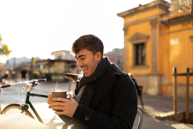 Homme souriant de coup moyen tenant une tasse