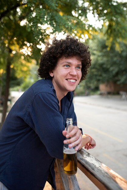 Homme souriant de coup moyen tenant un verre