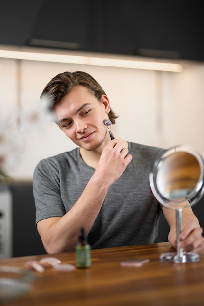 Photo gratuite homme souriant à coup moyen utilisant l'outil gua sha