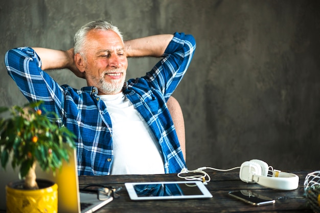 Photo gratuite homme souriant décontracté devant un ordinateur portable et une tablette numérique sur le bureau