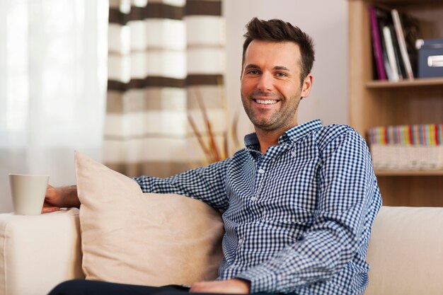 Homme souriant avec équipement de nettoyage dans le salon