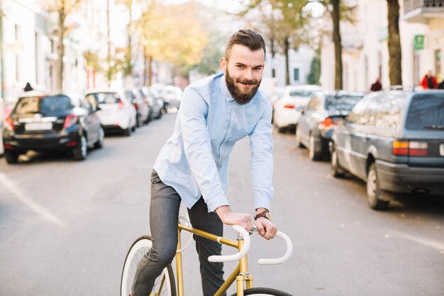 Homme souriant, faire du vélo le long de la route