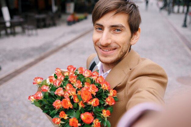 Homme souriant faisant selfie avec des fleurs