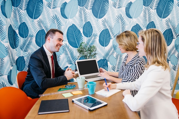 Photo gratuite homme souriant et les femmes qui travaillent à l'ordinateur portable