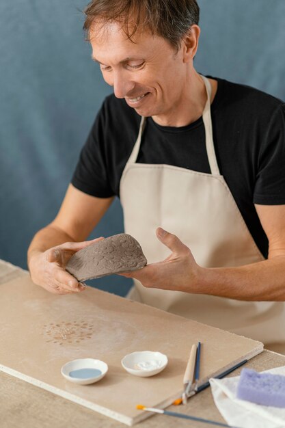 Homme souriant gros plan faisant de la poterie