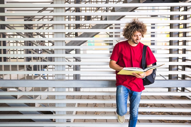 Homme souriant, lecture de livre près du mur