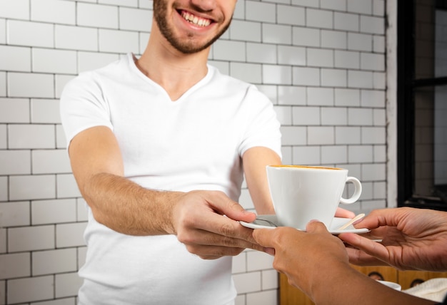 Homme souriant offrant une tasse de café